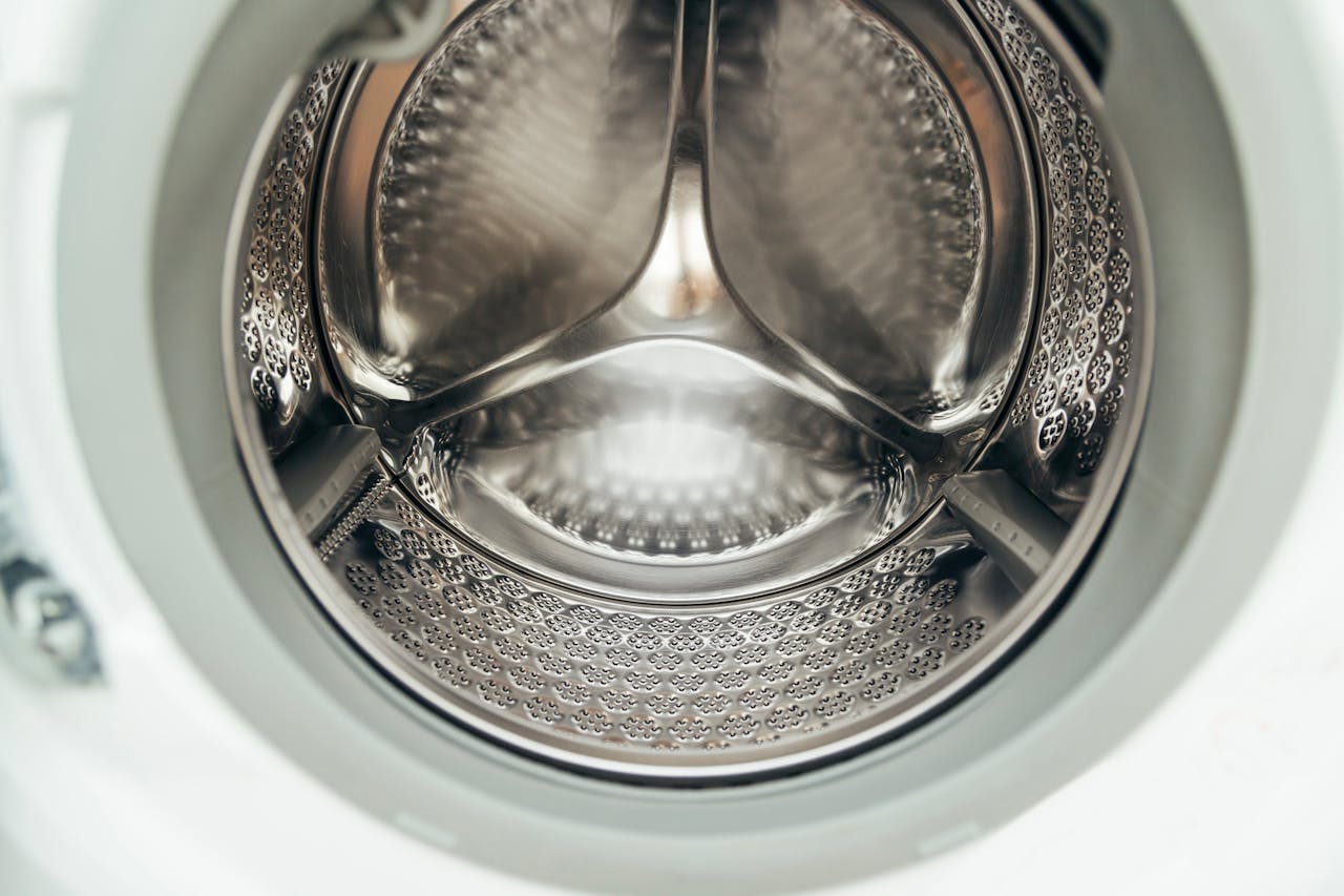 Detailed view of a clean, modern washing machine drum, showcasing shiny stainless steel interior.